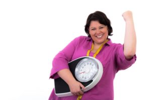 Frau mit besiegter Waage: Bei Arthrose Übergewicht erfolgreich abbauen
